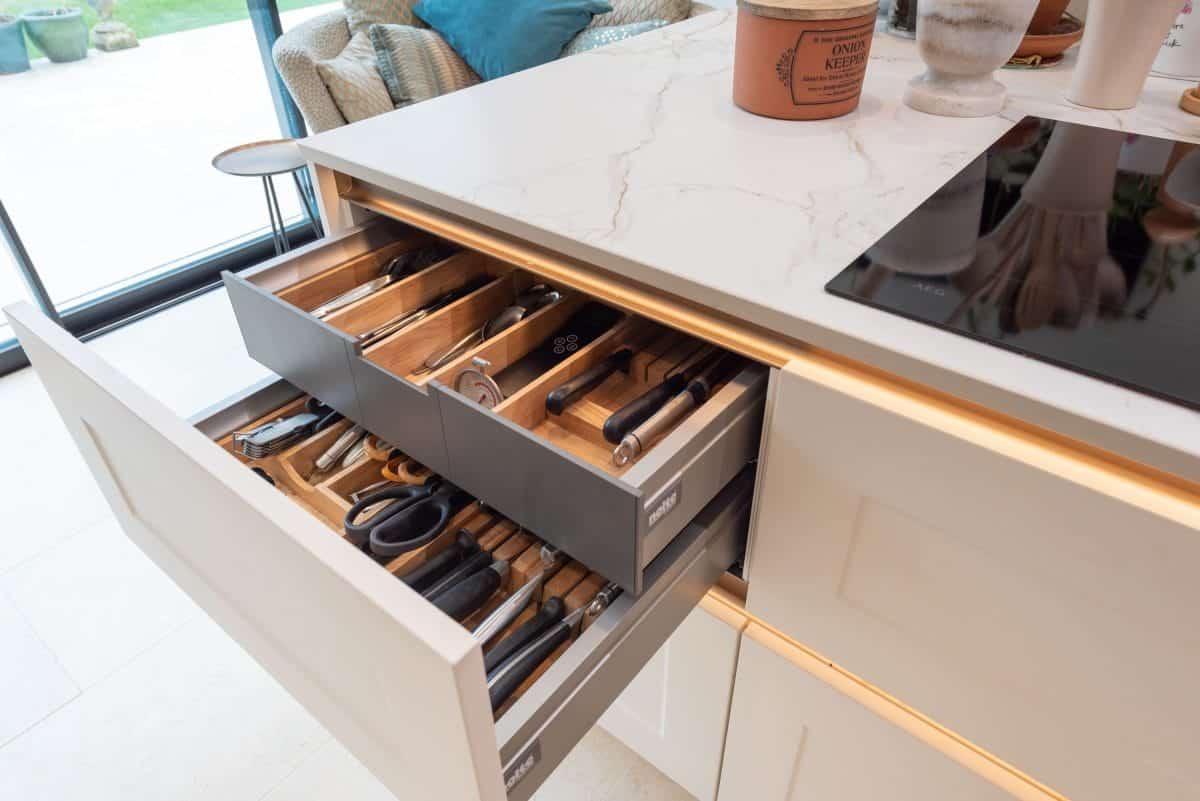 Organised kitchen cutlery drawer with wooden inserts, knife storage and quartz worktop above