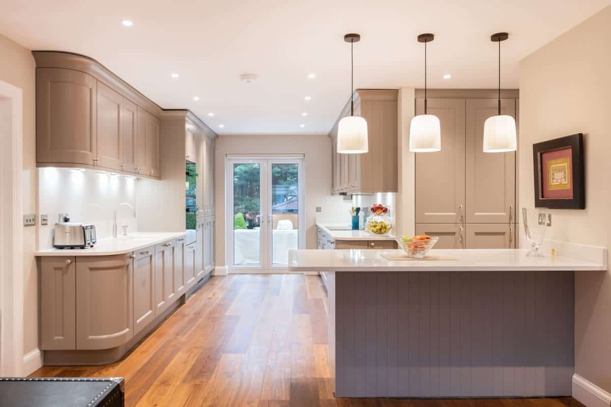 Ebstone taupe shaker kitchen with contrasting dark island, white quartz worktops and French doors opening to the garden