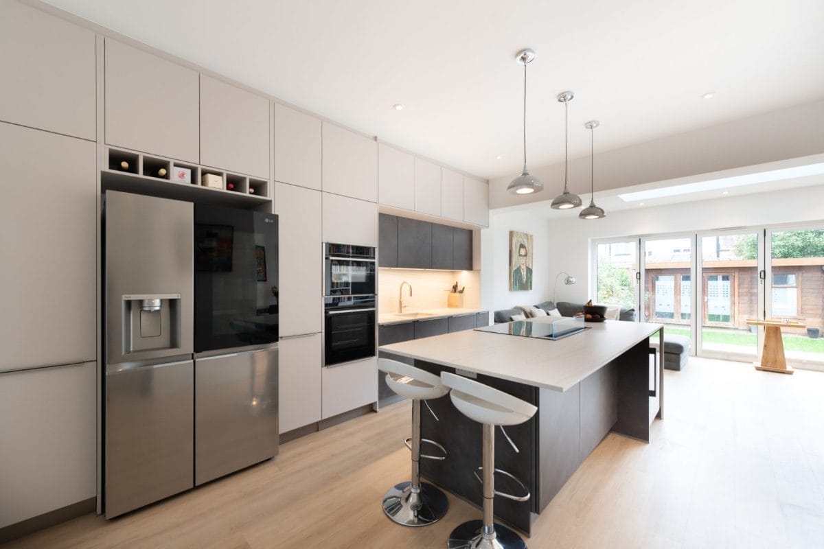 Ebstone light grey and graphite handleless kitchen with island seating, American fridge freezer and bifold doors to garden in West London home