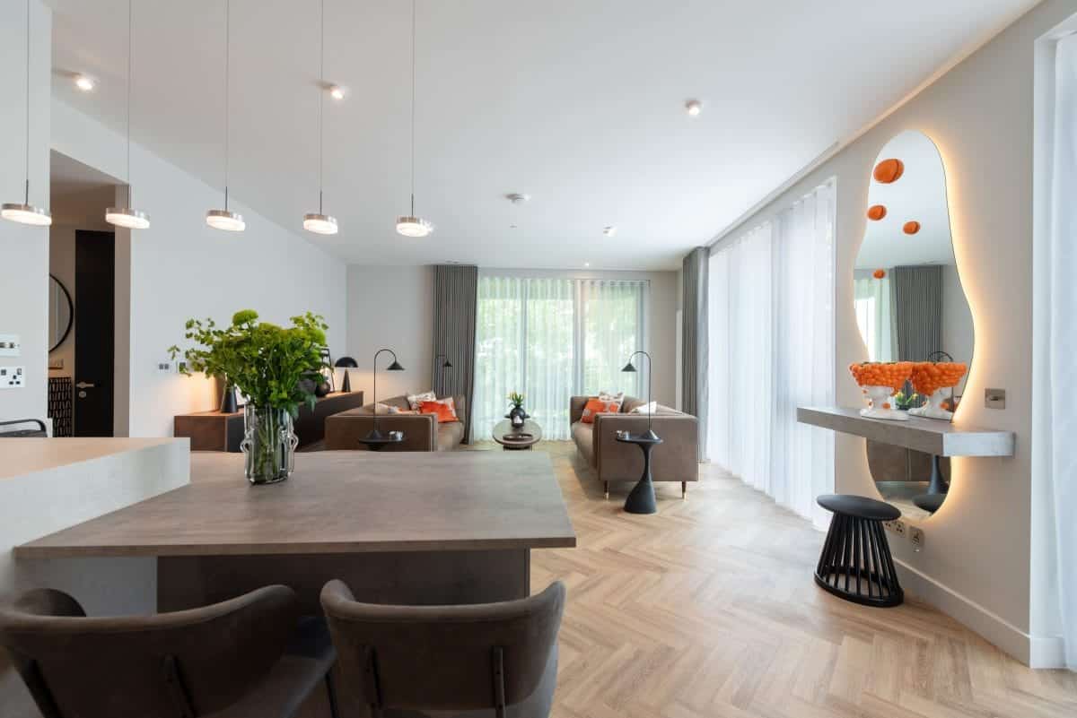Open plan kitchen and living space with wood effect island, neutral interiors and contemporary pendant lighting