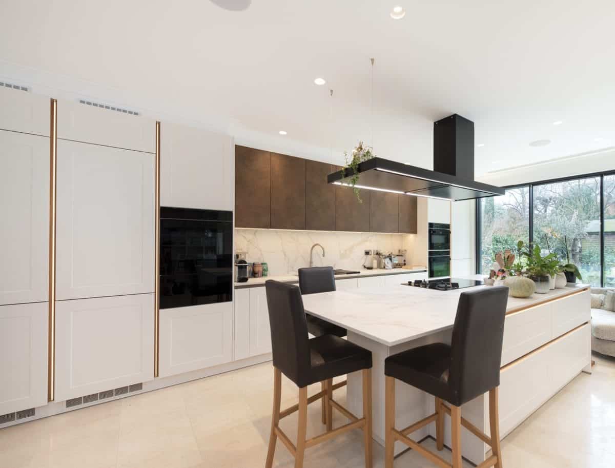 Contemporary white kitchen with integrated ovens, island hob and ceiling extractor