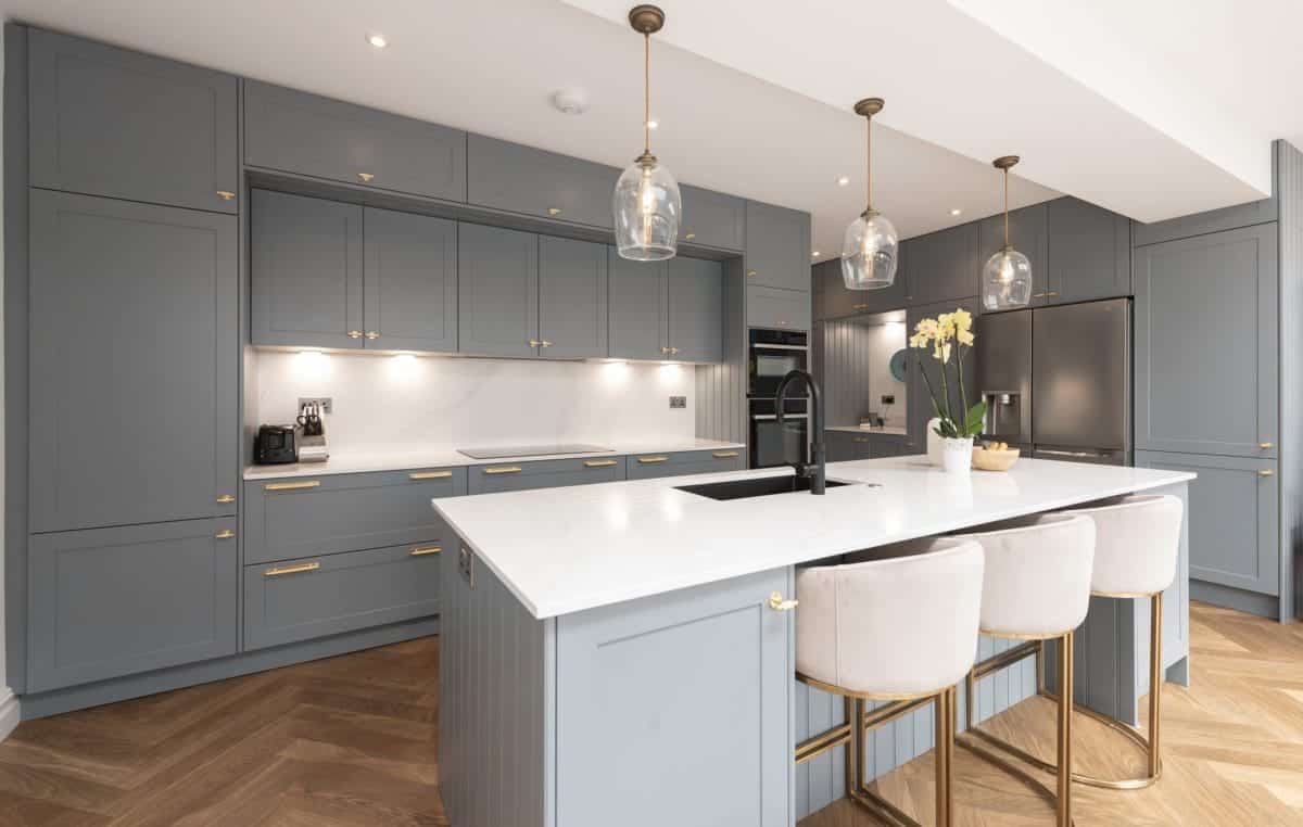 Grey shaker kitchen with white worktops, brass handles, statement island and pendant lighting
