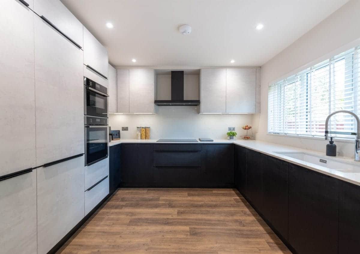Modern black and white handleless kitchen with wood flooring and integrated appliances by Ebstone Kitchens