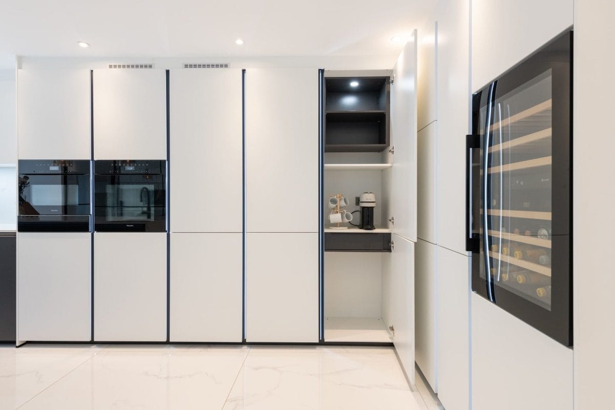 Modern handleless kitchen with integrated appliances and concealed coffee station by Ebstone Kitchens