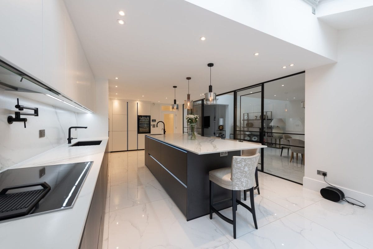 Modern bespoke kitchen with quartz worktops, dark island, white cabinetry and black framed glass partition