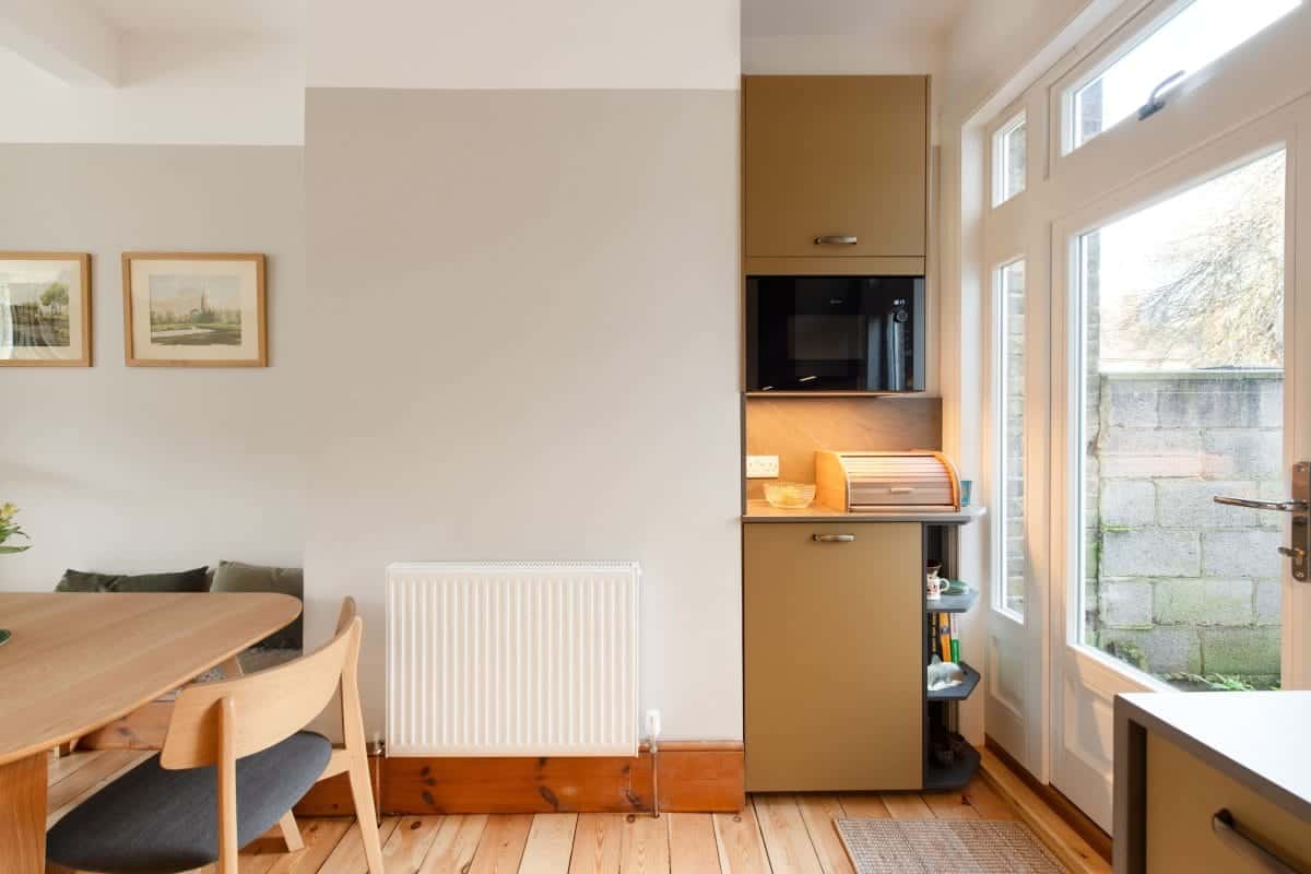 Compact bespoke kitchen storage with integrated microwave, small appliance shelf and dining area