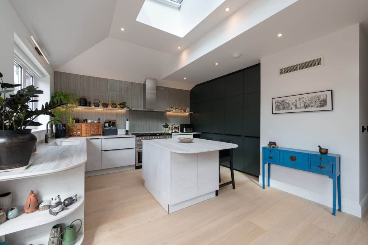 Bespoke kitchen with curved island, contrasting cabinetry and large rooflight