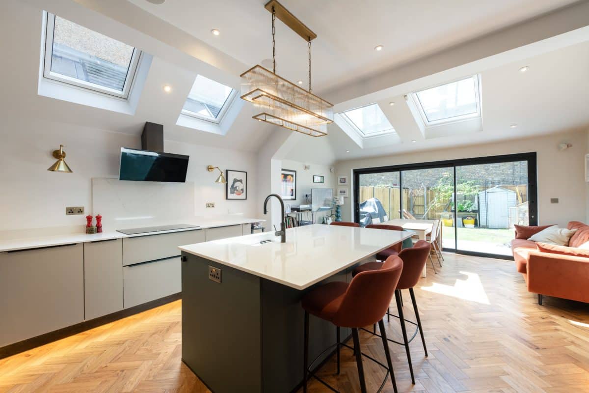 Open-plan kitchen extension with dark island, breakfast seating and garden doors